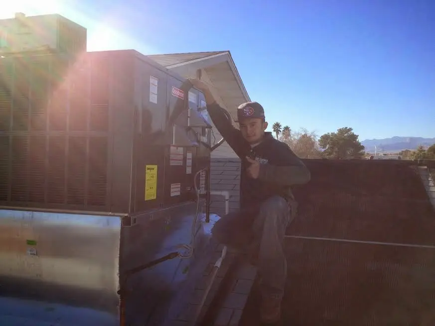 HVAC technician performing HVAC Inspection on a rooftop unit in Groton